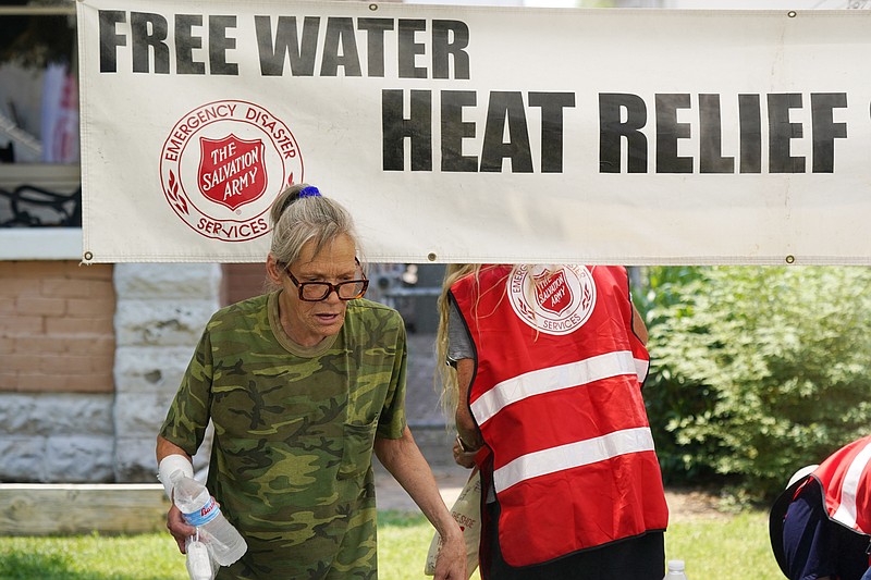A pedestrian takes a bottle of water at a Salvation Army hydration station during a heatwave as temperatures hit 115-degrees, Tuesday, June 15, 2021, in Phoenix. (AP Photo/Ross D. Franklin)