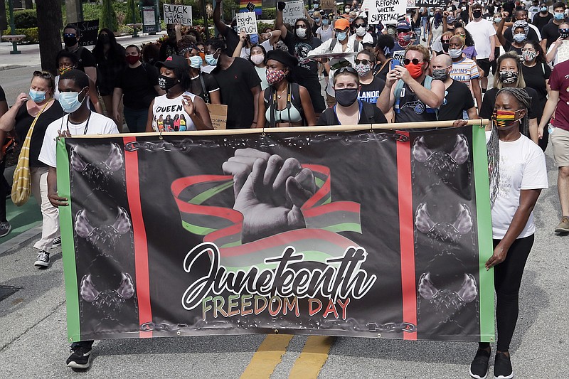 FILE - In this June 19, 2020, file photo, demonstrators march through downtown Orlando, Fla., during a Juneteenth event. Congress and President Joe Biden acted with unusual swiftness Thursday, June 17, 2021, in approving Juneteenth as a national holiday. That sent many states scrambling to clarify their policies on the celebration of slavery’s end. This year alone, Juneteenth bills hit roadblocks in Florida, Maryland, Ohio and South Dakota. (AP Photo/John Raoux, File)