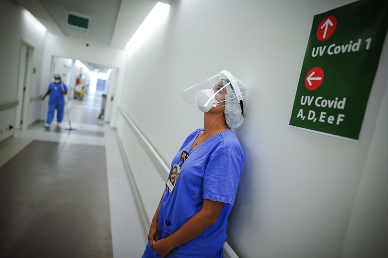 FILE - In this March 19, 2021 file photo, a health worker pauses in the ICU unit for COVID-19 patients at the Hospital das Clinicas in Porto Alegre, Brazil. As Brazil hurtles toward an official COVID-19 death toll of 500,000 — second-highest in the world — science is on trial inside the country and the truth is up for grabs. (AP Photo/Jefferson Bernardes, File)