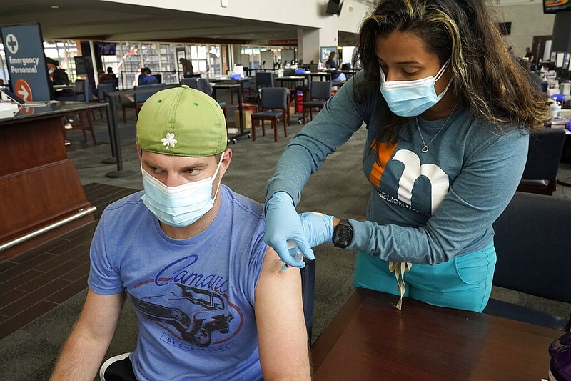 Kevin Fisher, of Quincy, Mass., left, receives his second shot of Moderna COVID-19 vaccine from RN Katherine Francisco, of Avon, Mass., right, at a mass vaccination clinic, Wednesday, May 19, 2021, at Gillette Stadium, in Foxborough, Mass. A month after every adult in the U.S. became eligible for the vaccine, a distinct geographic pattern has emerged: The highest vaccination rates are concentrated in the Northeast, while the lowest ones are mostly in the South.