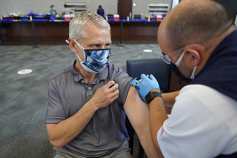 Paul Clasby, of Holliston, Mass., left, receives his second shot of Moderna COVID-19 vaccine from paramedic Jake Lees, of North Attleborough, Mass., right, at a mass vaccination clinic, Wednesday, May 19, 2021, at Gillette Stadium, in Foxborough, Mass. A month after every adult in the U.S. became eligible for the vaccine, a distinct geographic pattern has emerged: The highest vaccination rates are concentrated in the Northeast, while the lowest ones are mostly in the South.