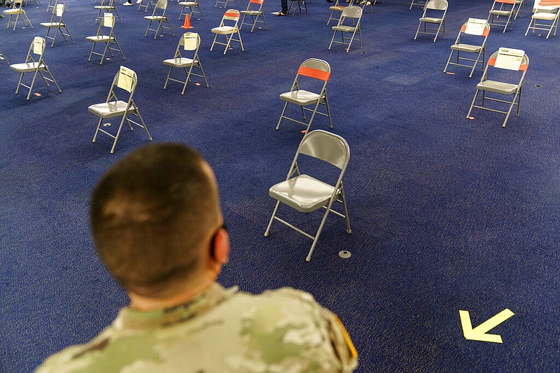 Rhode Island Army National Guard Sgt. Juan Gomez looks over the post inoculation waiting area at a coronavirus mass-vaccination site at the former Citizens Bank headquarters in Cranston, R.I., Thursday, June 10, 2021. The U.S. is confronted with an ever-growing surplus of COVID-19 vaccines, looming expiration dates and stubbornly lagging demand at a time when the developing world is clamoring for doses to stem a rise in infections.
