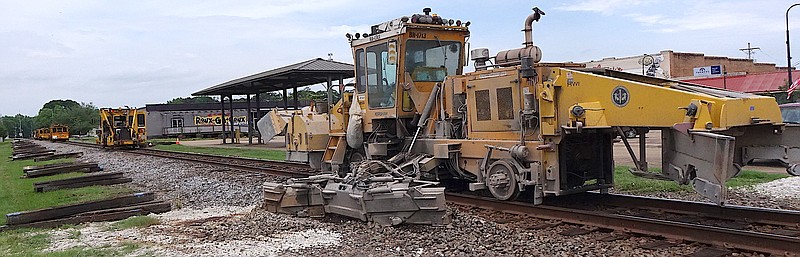This machine is a ballast regulator. The arm reaching out at center will align and smooth the rock, which is essential for strength of all parts of the track. At left are the old ties which have been pulled. The other machine is a spike puller.