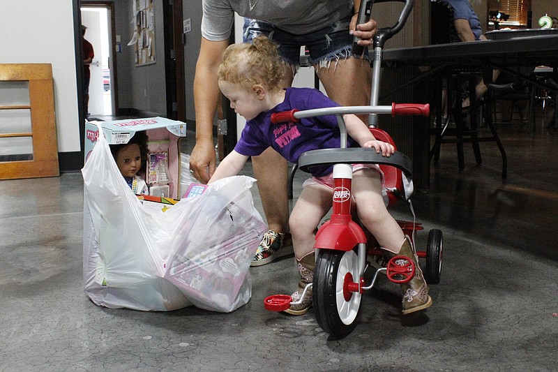 <p>Democrat photo/Austin Hornbostel</p><p>Peyton Rogers, 2, takes a look at the birthday gifts provided by members of the community from a seat on her new push tricycle. The California Eagles threw a surprise benefit for Peyton and her family a month removed from her suffering serious burns to both of her hands.</p>