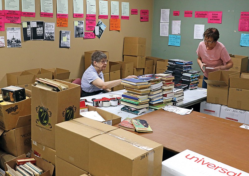 Jan Baker, left, sorts books Wednesday, June 23, 2021, at Missouri River Regional Library for the pop-up book sale that will take place in the art gallery Friday through Monday. Mary Zumwalt, right, sorts DVDs for a future sale. 