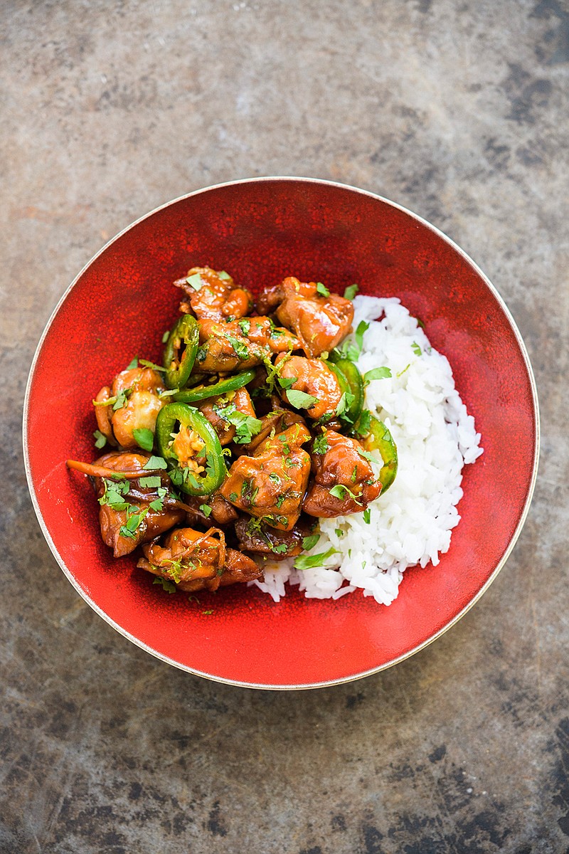 This image released by Milk Street shows a recipe for caramel chicken, made with shallots, ginger and a jalapeo chili. (Milk Street via AP)