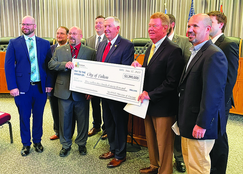 Gov. Mike Parson, center, visited Fulton City Hall on Tuesday morning to present Mayor Lowe Cannell, to Parson's right, with a loan check for $3.3 million through the state's Municipal Utility Loan Program. Officials with the Missouri Department of Natural Resources and its Division of Energy — which established the program — were also in attendance.