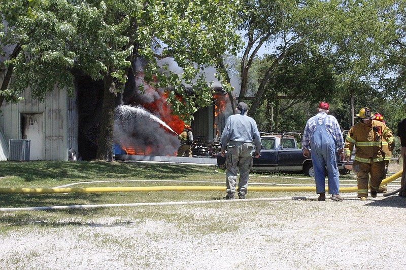 <p>Democrat photo/Austin Hornbostel</p><p>Onlookers watch as firefighters try to tame a fire, which burned for hours at a structure across the street from Putnam Chevrolet, last week.</p>