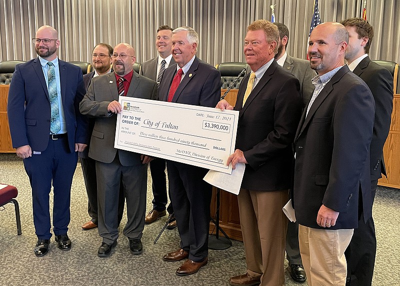 Ryan Boland/FULTON SUNGov. Mike Parson (center) visited Fulton City Hall on Tuesday morning to present Mayor Lowe Cannell (to Parson's right) with a loan check for $3.3 million through the state's Municipal Utility Loan Program. Officials with the Missouri Department of Natural Resources and its Division of Energy — which established the program — were also in attendance.