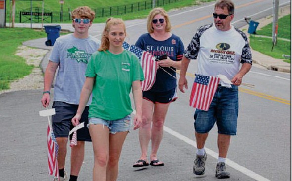 On Friday, July 2, 2021, Sprenger family members return to their truck to move to a different location where they will continue to put out small American flags for Independence Day.