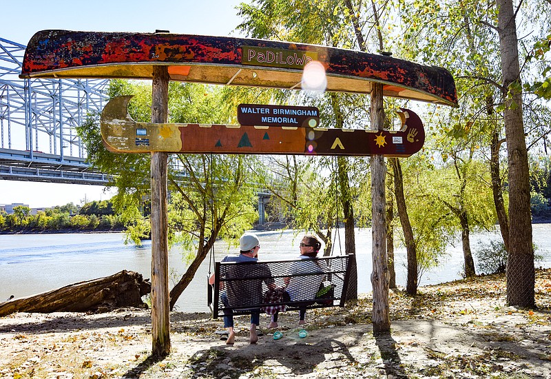 Julie Smith/News Tribune
John, left, and Brandy Booyer enjoy the feel of their feet in the dirt as they kicked of their shoes and relaxed on the bank of the Missouri River Monday, seated in a swing, watching the sun reflect off the water as it flowed by. The day’s temperature didn’t make it feel much like October but the wind that is blowing in a front that will cause mid-week temperatures to drop into the the mid-50’s for a high, will remind you that it is the 10th month.