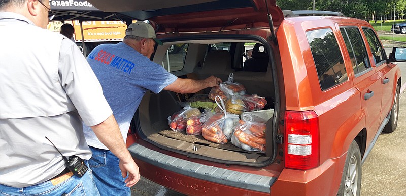 Steve Rogers, left, and Jimmy Norwood load up another recipient's vehicle with food during Thursday's food distribution, courtesy of 50k Souls and the East Texas Food Bank. Rogers, a fire chief with the Nash Fire Department and Norwood, a board member of the Nash City Council, and both members of the Sunrise Rotary Club.