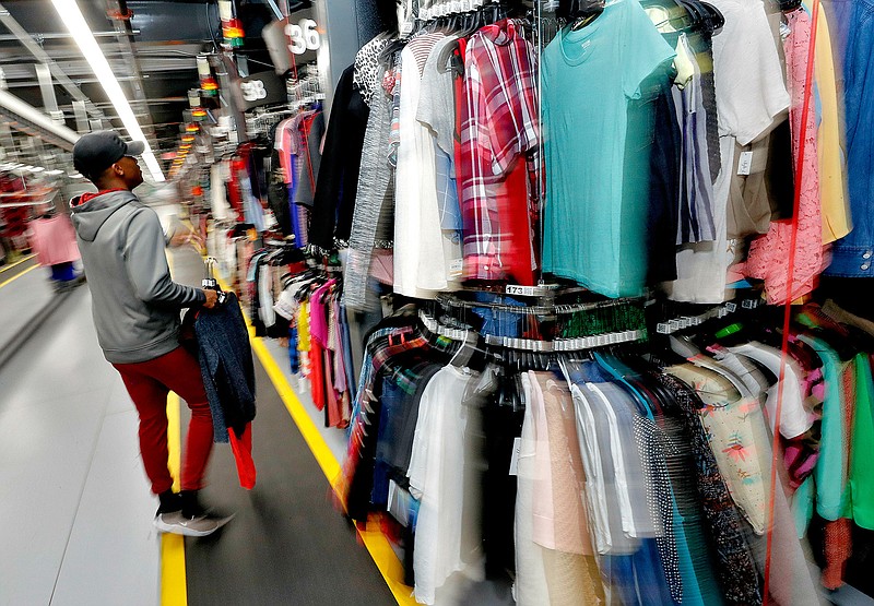 Willie Walton hangs clothing on a three-tiered conveyor system at the ThredUp sorting facility in Phoenix on March 12, 2019.  A wardrobe purge is on for some as vaccinations have taken hold, restrictions have lifted and offices reopen or finalize plans to do so. The primary beneficiaries are secondhand clothing marketplaces, and brick-and-mortar donation spots. (AP Photo/Matt York, File)