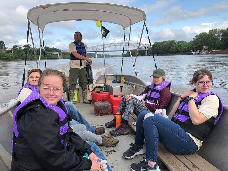 In back, Steve Schnarr, executive director of Missouri River Relief, drives a boat along the Missouri River during Sunday's river cleanup event held in conjunction witih the Conservation Federation of Missouri. It's one of three boats that cleaned the river banks in different locations near Jefferson City. Volunteers, from left, are Abby McMurtry, Moira Crowell, Mya Thomas and Kaley Brittain. 