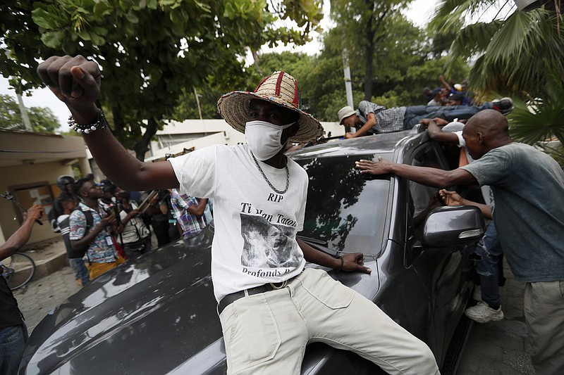 Supporters of former Senator Steven Benoit shout outside the courthouse as he departs after being called in for questioning, in Port-au-Prince, Monday, July 12, 2021. Prosecutors have requested that high-profile politicians like Benoit meet officials for questioning as part of the investigation into the assassination of President Jovenel Moise. (AP Photo/Fernando Llano)