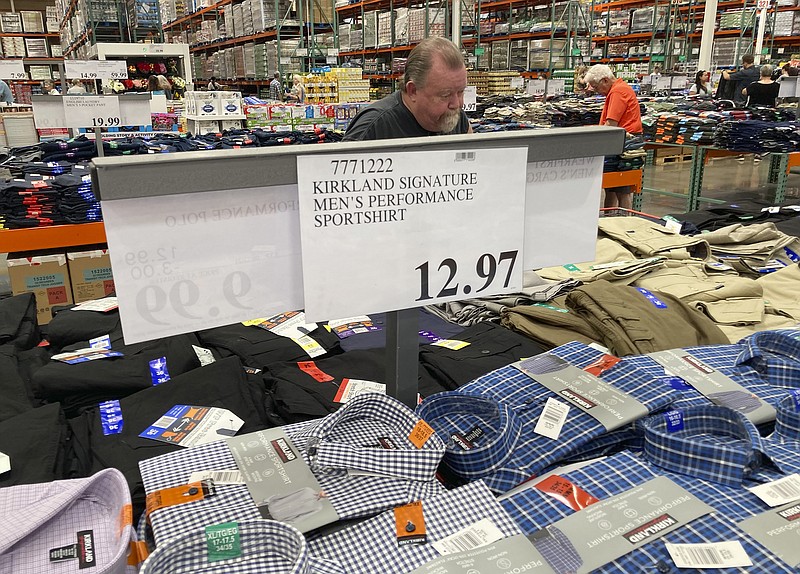 A sign displays the price for shirts as a shopper peruses the offerings at a Costco warehouse on Thursday, June 17, 2021, in Lone Tree, Colo. American consumers faced a third straight monthly surge in princes in June, the latest sign that a rapid reopening of the economy is fueling a pent-up demand for goods and services that in many cases remain in short supply.  (AP Photo/David Zalubowski)