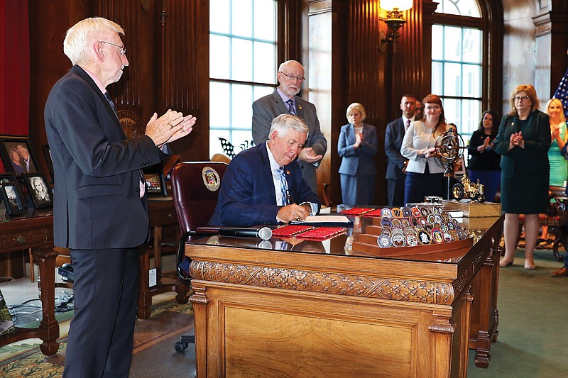 Missouri Gov. Mike Parson signs HB 557 on Tuesday, July 14, 2021, as Rep. Rudy Veit stands by and applauds in the governor's office at the Capitol. 