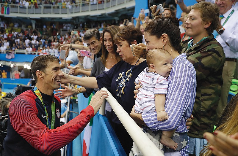 In this Aug. 9, 2016, file photo, Michael Phelps celebrates after winning a gold medal in the men's 200-meter butterfly with his mother Debbie, fiance Nicole Johnson and baby Boomer at the 2016 Summer Olympics in Rio de Janeiro, Brazil.
