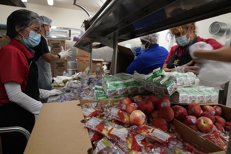 Los Angeles Unified School District food service workers from left, Tomoko Cho, Aldrin Agrabantes, April Thomas, and Marisel Dominguez, pre-package hundreds of free school lunches in plastic bags on Thursday, July 15, 2021, at the Liechty Middle School in Los Angeles. Flush with cash from an unexpected budget surplus, California is launching the nation's largest statewide universal free lunch program. When classrooms open for the fall term, every one of California's 6.2 million public school students will have the option to eat school meals for free, regardless of their family's income. (AP Photo/Damian Dovarganes)