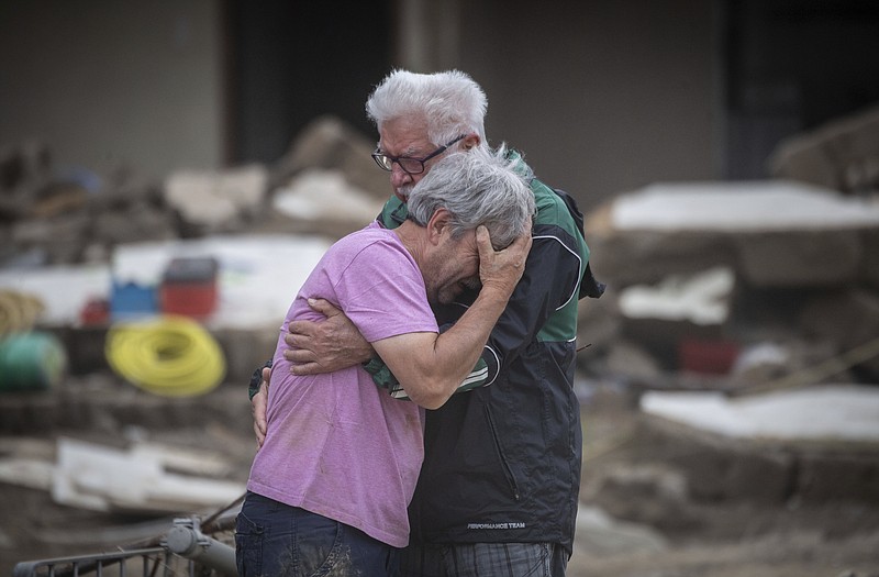 Two brothers weep in each other's arms in front of their parents' house, which was destroyed by the flood in Altenahr, Germany, Monday, July 19, 2021. Numerous houses in the town were completely destroyed or severely damaged, there are numerous fatalities. (Boris Roessler/dpa via AP)