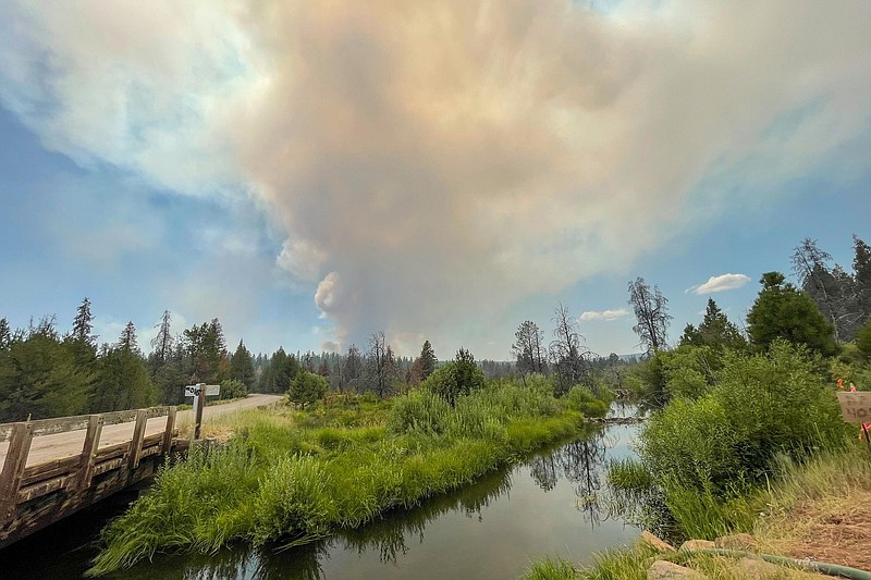 In this photo provided by the Bootleg Fire Incident Command, the Bootleg Fire burns in the background behind the Sycan Marsh in southern Oregon on Saturday, July 17, 2021. The destructive Bootleg Fire, one of the largest in modern Oregon history, has already burned more than 476 square miles (1,210 square kilometers), an area about the size of Los Angeles.  (Bootleg Fire Incident Command via AP)