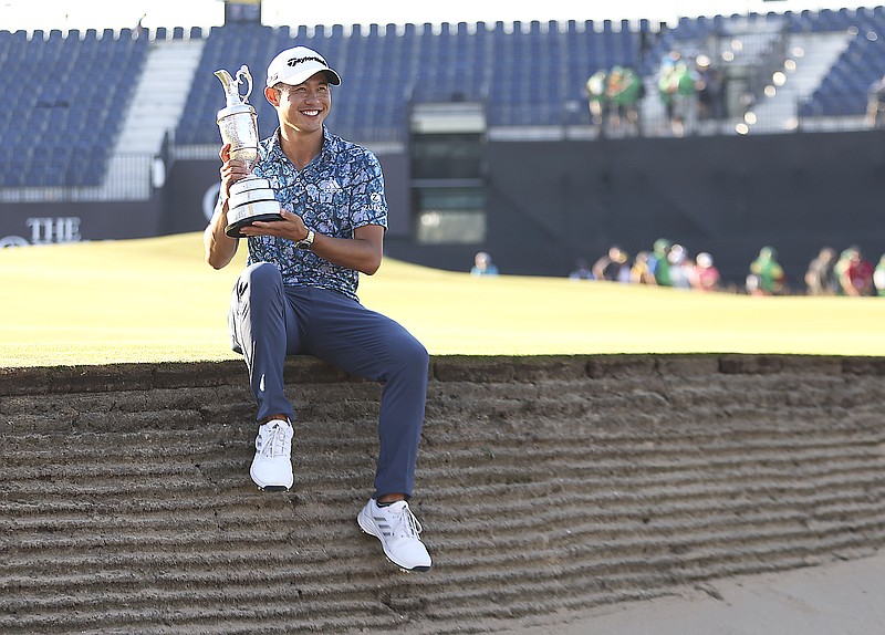 Collin Morikawa holds up the claret jug trophy as he poses for photographers on the 18th green Sunday after winning the British Open at Royal St. George's in Sandwich, England.