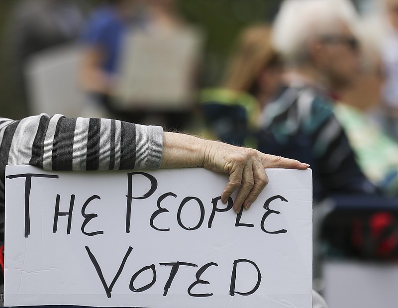 FILE - In this April 27, 2021, file photo, a rally attendee props up a sign with her hand while listening to speakers at the Medicaid expansion rally at the Missouri State Capitol in Jefferson City. The Missouri Supreme Court has vacated a lower court's decision in the state's Medicaid expansion case, agreeing that the voter-approved plan to offer Medicaid to more people should stand. The unanimous decision on Thursday, July 22, 2021, sends the case back to Cole County Circuit Court. (Liv Paggiarino/The Jefferson City News-Tribune via AP, File)