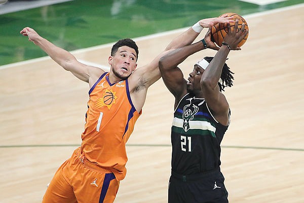 Jrue Holiday of the Bucks  is fouled by Devin Booker of the Suns during Tuesday night's Game 6 of the NBA Finals in Milwaukee. Holiday and Booker have joined the U.S. Olympic team in Tokyo.