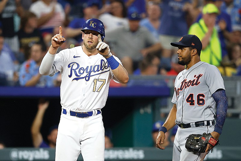 Hunter Dozier of the Royals gestures after hitting a triple while standing next to Tigers third baseman Jeimer Candelario during the sixth inning of Friday night's game at Kauffman Stadium in Kansas City.