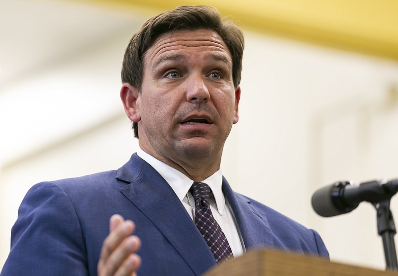 FILE - This May 4 2021 file photo shows Florida Gov. Ron DeSantis, center, speaks during a news conference at West Miami Middle School in Miami.  Several states scaled back their reporting of COVID-19 statistics this July 2021, just as cases across the country started to skyrocket, depriving the public of real-time information on outbreaks, cases, hospitalizations and deaths in their communities. (Matias J. Ocner/Miami Herald via AP, File)