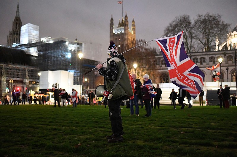 In this file photo dated Friday, Jan. 31, 2020, a Brexit supporter holds a British flag with the slogan "Leave Means Leave" during a rally near parliament in London.  Millions of Europeans who have freely lived, worked and studied in the U.K. for decades, now have to apply to stay under the "settlement" plan, but the deadline for applications is Wednesday June 30, 2021. From Thursday July 1, any European person who hasn't applied will lose their legal right to work, rent housing, access some welfare and hospital treatments in the U.K. and campaigners say many thousands may not have applied by the deadline.  (AP Photo/Alberto Pezzali, FILE)