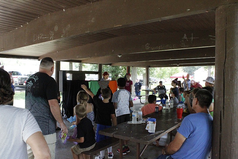 <p>Democrat photo/Austin Hornbostel</p><p>Children and their families gather under the shelter house to watch a puppet show Saturday afternoon at Proctor Park as part of Abundant Life United Pentecostal Church’s community festival. The congregation is new to the community, having hosted its first service Sunday evening at the Moniteau County Library.</p>