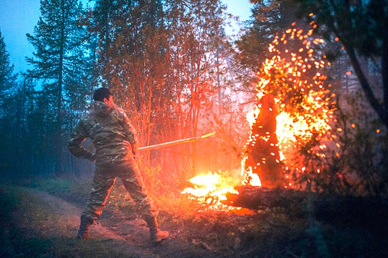A member of volunteers crew mops up spot fires at Gorny Ulus area west of Yakutsk, Russia, Thursday, July 22, 2021. The hardest hit area is the Sakha Republic, also known as Yakutia, in the far northeast of Russia, about 5,000 kilometers (3,200 miles) from Moscow.  About 85% of all of Russia's fires are in the republic, and heavy smoke forced a temporary closure of the airport in the regional capital of Yakutsk, a city of about 280,000 people. (AP Photo/Ivan Nikiforov)