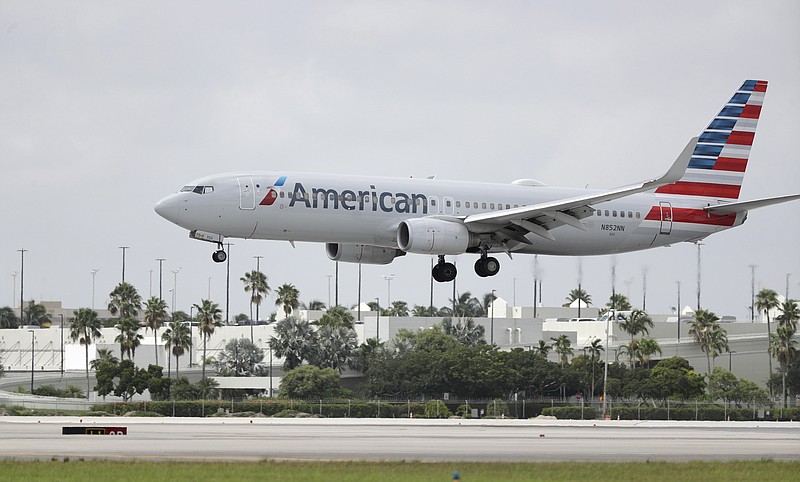 FILE - In this July 27, 2020, file photo, an American Airlines Boeing 737-823 lands at Miami International Airport in Miami. Flight attendants at American Airlines say they are sometimes forced to sleep in airports because the airline fails to book hotel rooms for employees on the road. Unions for flight attendants and pilots filed grievances against American this week, charging the airline with violating their contracts and putting employees in danger. The president of the flight attendants' union says some of her members have slept outside baggage claim because they didn't have a hotel room. Leaders of the pilots' union say pilots have been put in unsafe hotels or told to walk to the hotel in the middle of the night when flights arrive late. (AP Photo/Wilfredo Lee, File)