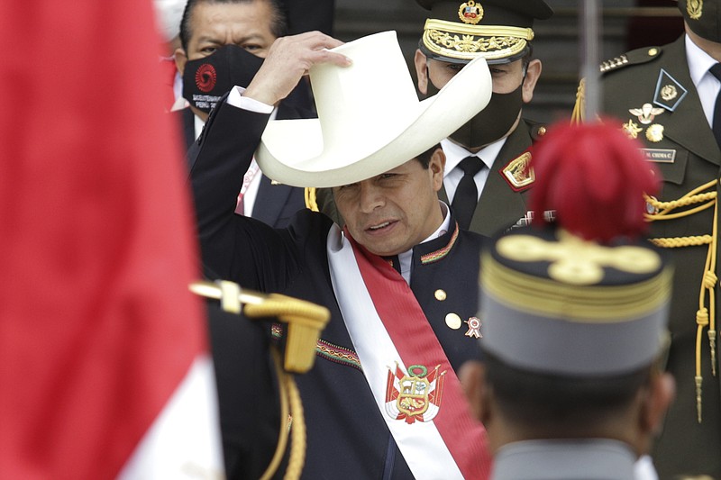 Peru's newly sworn-in President Pedro Castillo puts his hat back on after taking it off momentarily to acknowledge the Peruvian flag held by soldiers outside Congress on his inauguration day in Lima, Peru, Wednesday, July 28, 2021. The rural teacher popularized the phrase “No more poor in a rich country,” and stunned millions of Peruvians and observers by advancing to the runoff. (AP Photo/Francisco Rodriguez)