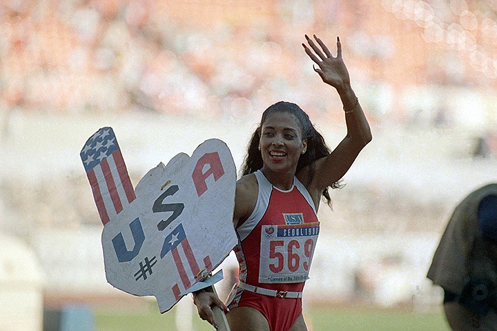 In this Sept. 29, 1988, file photo, Florence Griffith Joyner, of the United States, waves to spectators as she holds a sign following her world record performance in the finals of the women's 200-meters race, in Seoul, South Korea. The name Flo-Jo is popping up quite a bit these days with sprinters creeping closer to her record times in the women's 100 and 200 races. The late Florence Griffith Joyner has held both marks for three decades. (AP Photo/Lennox McLendon, File)