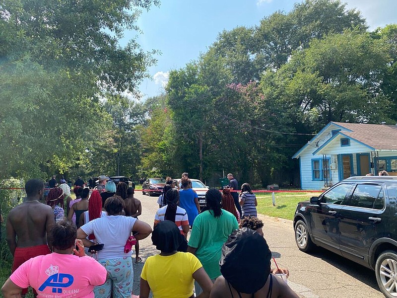 Several onlookers gather Thursday in front of a house on Parish Street in Texarkana, Texas, where police found a vehicle associated with the suspect in a double shooting behind a house on the street. The suspect was found and arrested on the Arkansas side.