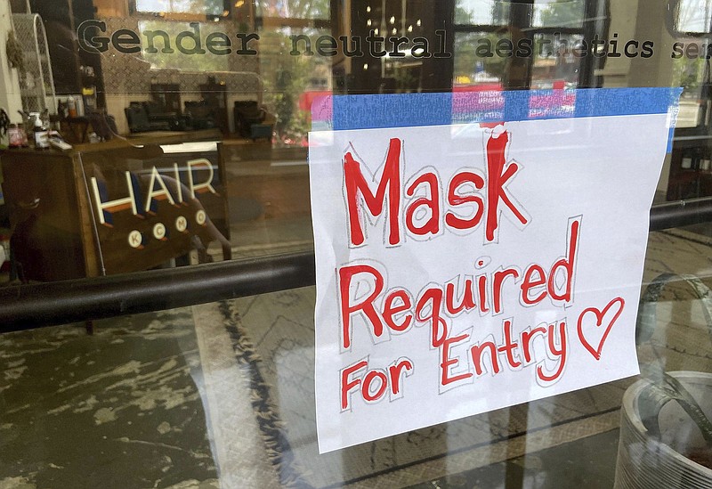 FILE - This July 2021 file photo shows a sign on the door of a hair salon informing patrons that masks are required to be in the business in Kansas City, Mo. St. Louis County's top elected official insisted Wednesday, July 28, 2021 that a mask mandate remained in place even though the county commission voted to overturn it. Across the state, meanwhile, Kansas City issued its own order in an effort to stem a rise in COVID-19 cases that is straining hospitals, leading to an immediate threat of a lawsuit.(Jill Toyoshiba/The Kansas City Star via AP, File)