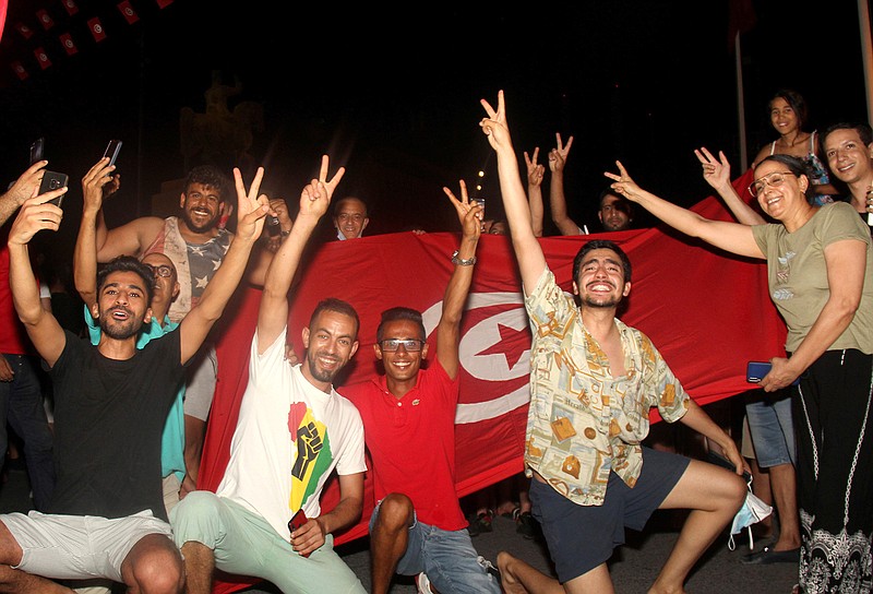 In this July 25, 2021 file photo, demonstrators celebrate with a Tunisian national flag during a rally after the president suspended the legislature and fired the prime minister in Tunis, Tunisia. Days of political turmoil in Tunisia over the economy and the coronavirus have left its allies in the Middle East, Europe and the United States watching to see if the fragile democracy will survive. (AP Photo/Hedi Azouz, File)