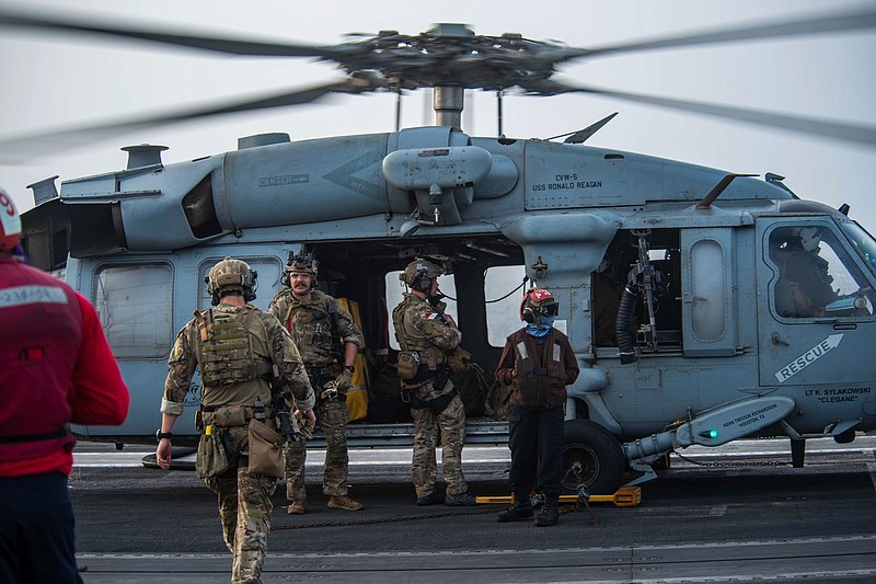In this photo provided by the U.S. Navy, sailors assigned to an explosive ordnance unit board an MH-60S Seahawk helicopter on the flight deck of aircraft carrier USS Ronald Reagan to head to an oil tanker that was attacked off the coast of Oman in the Arabian Sea on Friday, July 30, 2021. An attack on an oil tanker linked to an Israeli billionaire killed two crew members off Oman in the Arabian Sea, authorities said Friday, marking the first fatalities after years of assaults targeting shipping in the region. (Mass Communication Specialist 2nd Class Quinton A. Lee/U.S. Navy, via AP)