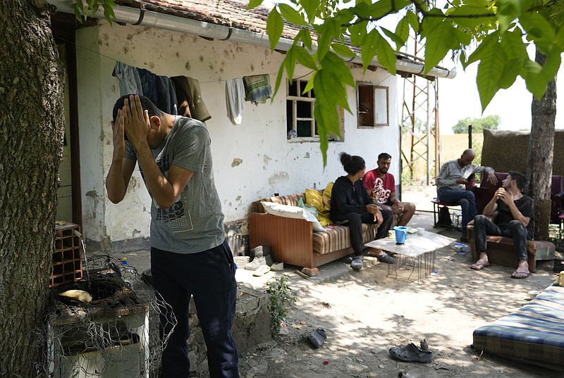 Migrants rest in front of an abandoned house in the village of Majdan, Serbia, Thursday, July 22, 2021. Empty or abandoned houses serve as temporary homes to people who fled their own homes in the Middle East, Africa or Asia with an aim to start a new life somewhere else. (AP Photo/Darko Vojinovic)