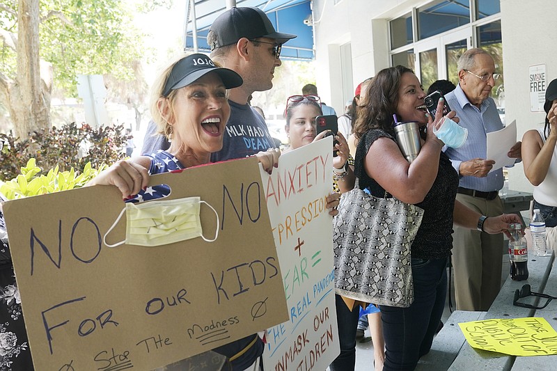 Joann Marcus of Fort Lauderdale, left, cheers as she listens to the Broward School Board's emergency meeting, Wednesday, July 28, 2021, in Fort Lauderdale, Fla. A small but vocal group spoke vehemently against masks, saying their personal rights were being eroded and their children were suffering socially. (AP Photo/Marta Lavandier)