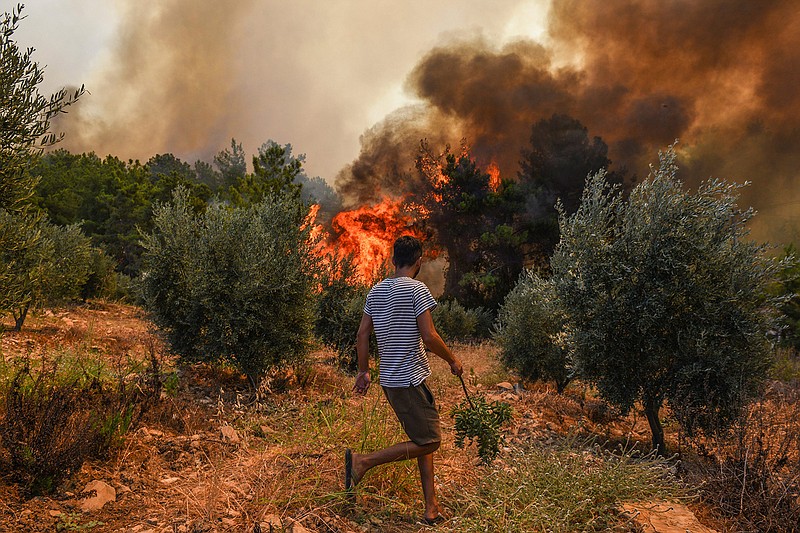 A man walks toward wildfires in Kacarlar village near the Mediterranean coastal town of Manavgat, Antalya, Turkey, Saturday, July 31, 2021. The death toll from wildfires raging in Turkey's Mediterranean towns rose to six Saturday after two forest workers were killed, the country's health minister said. Fires across Turkey since Wednesday burned down forests, encroaching on villages and tourist destinations and forcing people to evacuate. (AP Photo)