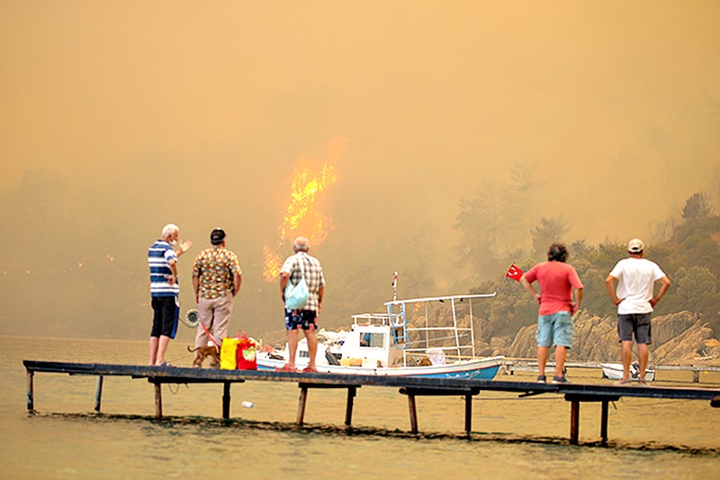 Tourists wait to be evacuated from smoke-engulfed Mazi area as wildfires rolled down the hill toward the seashore, in Bodrum, Mugla, Turkey, Sunday, Aug. 1, 2021. More than 100 wildfires have been brought under control in Turkey, according to officials. The forestry minister tweeted that five fires are continuing in the tourist destinations of Antalya and Mugla. (AP Photo/Emre Tazegul)