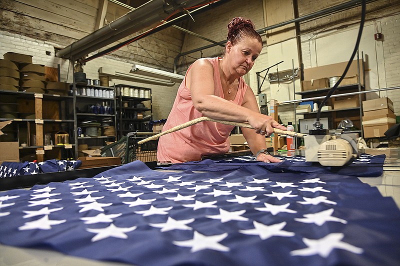 Debbie Wademan, production supervisor, cuts the stars to proper length to make American flags at North American Manufacturing on June 28, 2021 in Scranton, Pa. Since 2016, the staff at North American Manufacturing on Barring Avenue has meticulously produced about 8,000 full-size American flags each year, which are sold to the Defense Logistics Agency and awarded to government retirees. (Jason Farmer/The Times-Tribune via AP)