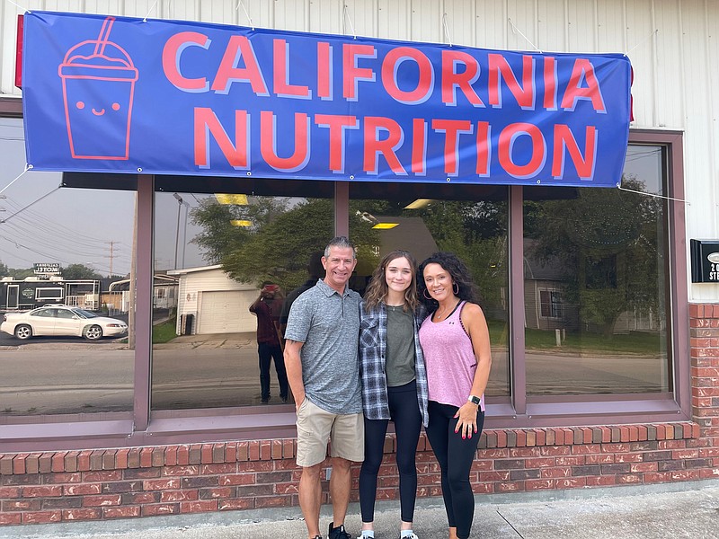 <p>Democrat photo/Kaden Quinn</p><p>California Nutrition owner April Reed, right, is pictured here with daughter Brehn, center, and husband Lindell, left, as they celebrate their grand opening.</p>