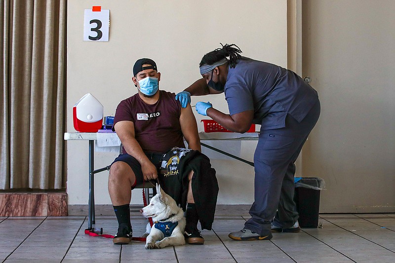 Joel Jurez, 22, holds hid dog Yuki as medical assistant Adrian Davis administers a COVID-19 vaccine at a vaccination clinic at St. Patrick's Catholic Church on April 9, 2021, in Los Angeles. (Irfan Khan/Los Angeles Times/TNS)