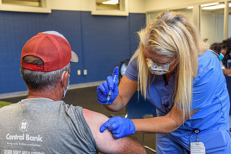 In this August 2021 photo, Lincoln University hosts a CoVid-19 vaccination clinic being administered by Community Health Center of Central Missouri inside Jason Gymnasium. Doug Moeller, who works at Lincoln University's Carver Farm receives a shot from CHCCM's Teressa Jacoby.