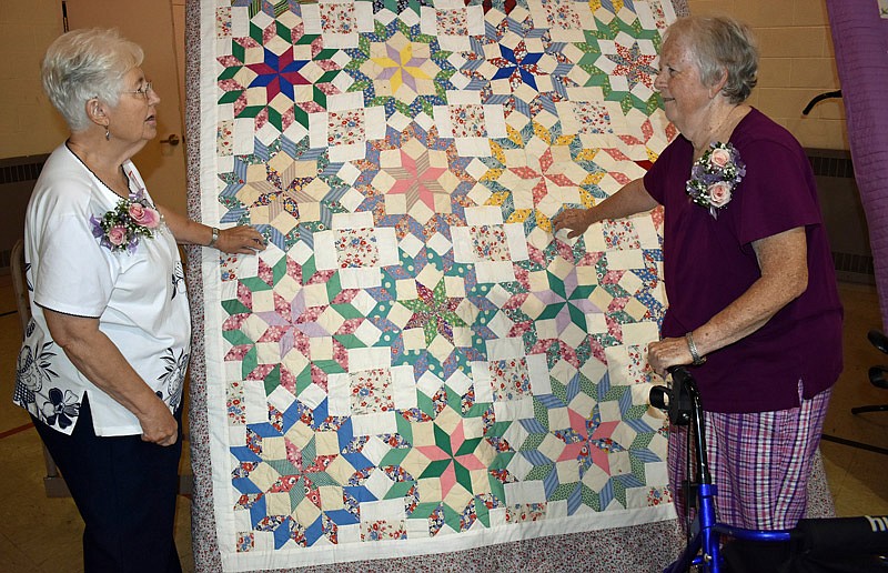Mary Ann Pearre (left) and Linda Heller look over one of the quilts they created Sunday, Aug. 15, 2021, while it was on display at a luncheon celebrating the 100th anniversary of Martha Circle, the quilting guild at Central Church in Jefferson City.