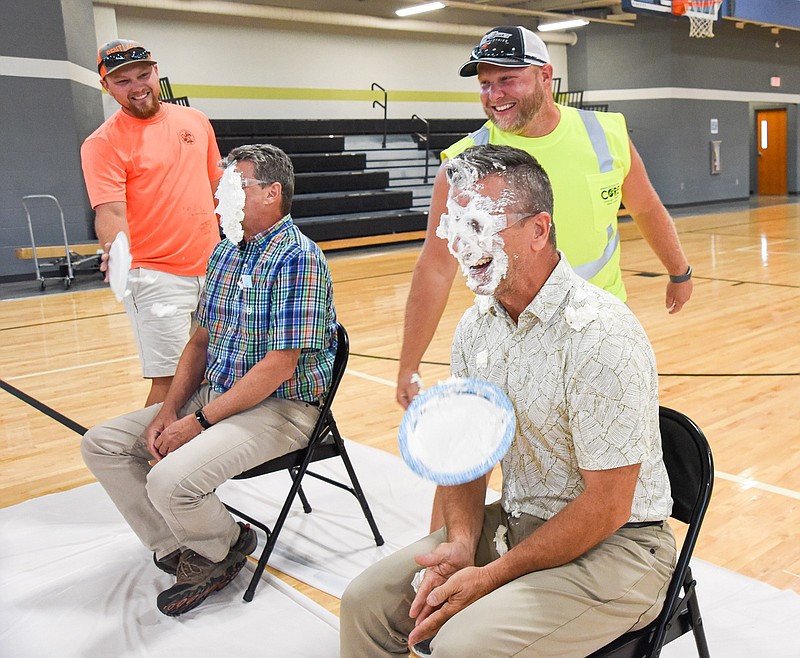 Matt Eveler, right, and Nick Bax, left, hit Todd Spalding, right, and Sonny Sanders, in background, during Thursday's fundraiser by city employees to benefit the United Way at the Line. Eveler and Bax won the corn hole tournament that put them in the position to smear the sweet cream in division directors' faces. 